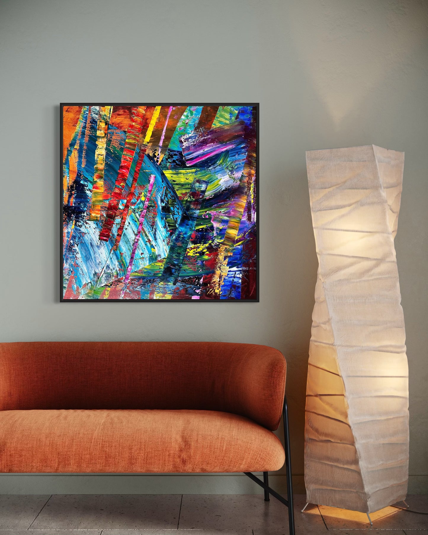 Colorful abstract painting on a wall above an orange sofa with a tall floor lamp.