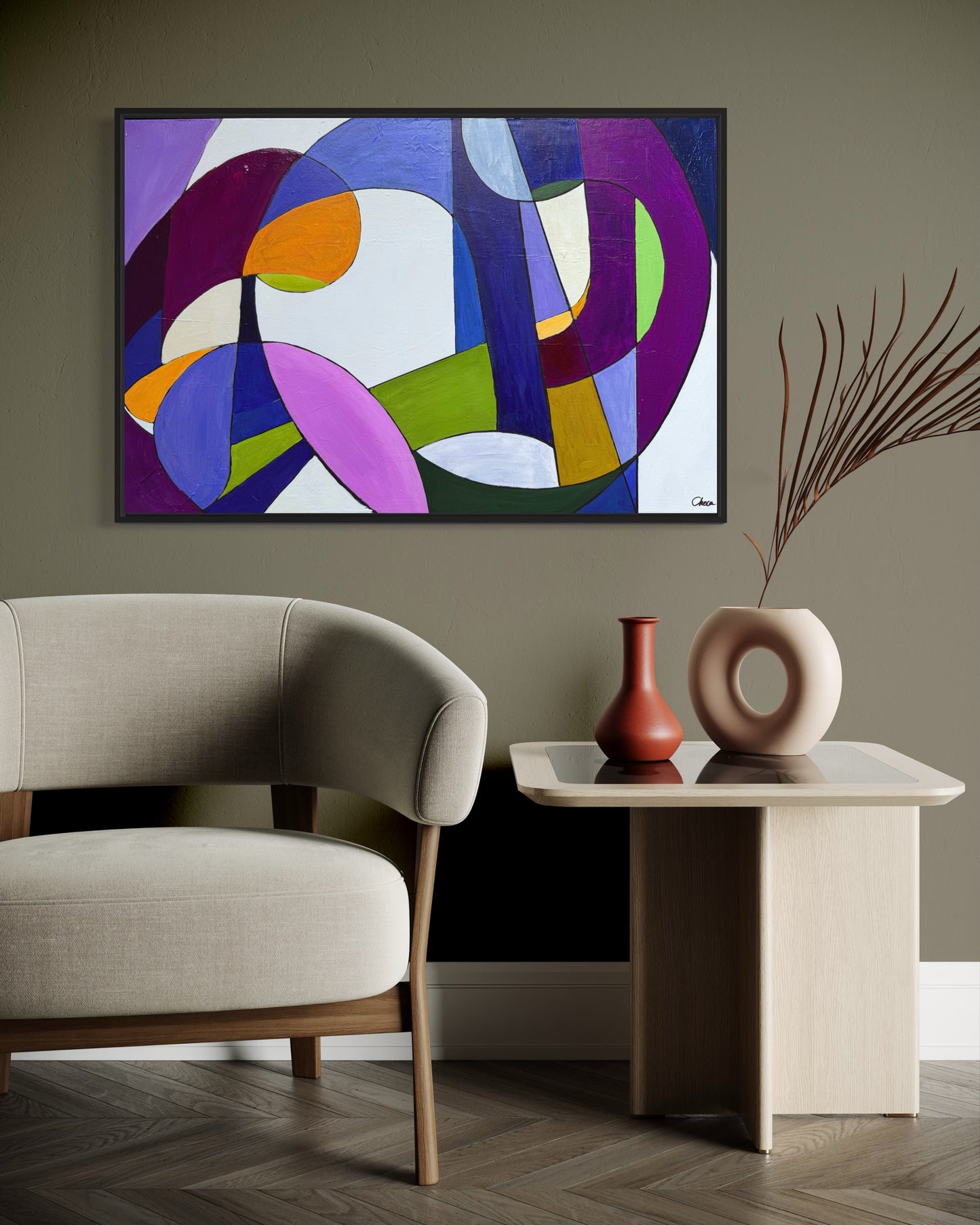 Abstract art piece on a wall above a chair and side table with decorative vases.