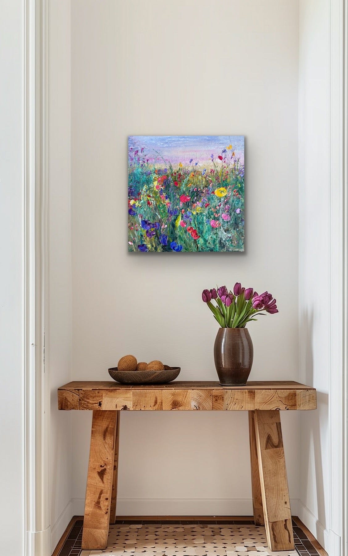 Framed fine art print of ‘Flower Field at Dusk’ by Maria-Victoria Checa displayed in a hallway above a wooden console with a vase of tulips.