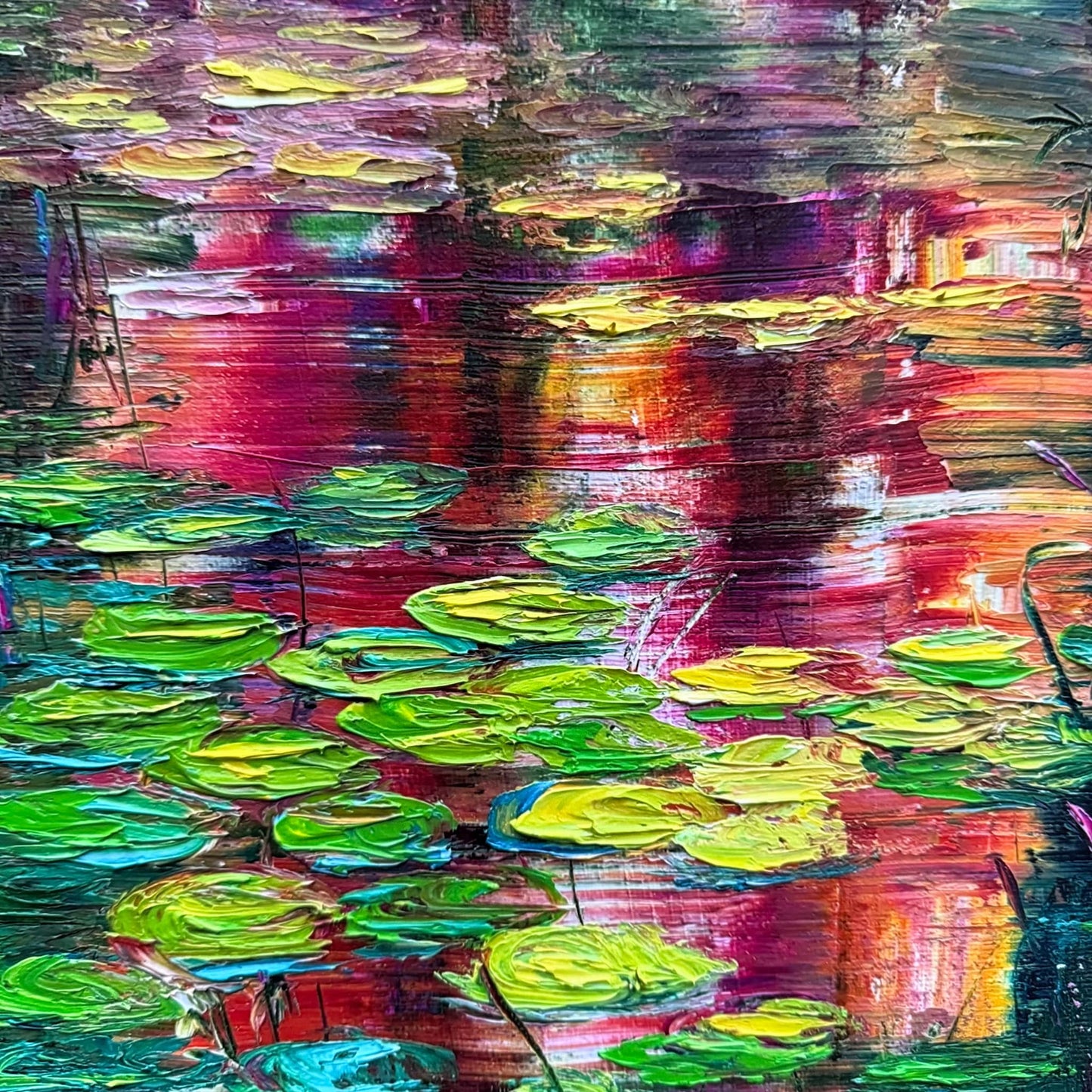 Detail of Sunset Lilies by Maria-Victoria Checa showing textured palette knife lily pads in chartreuse and green against bold crimson and magenta sunset reflections on a deep teal pond.
