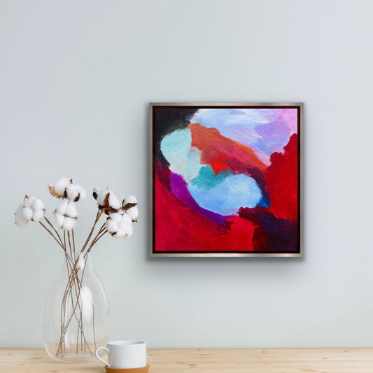 Eternity abstract acrylic painting by Maria-Victoria Checa in a silver float frame displayed on a pale blue wall beside cotton stems in a bright minimal interior