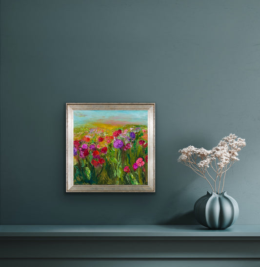 Framed painting by impressionist artist Maria-Victoria Checa of a floral field on a dark grey wall with a vase of flowers below.