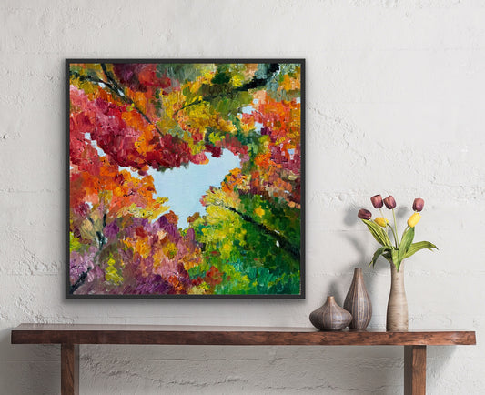 Framed impressionist landscape painting by Maria-Victoria Checa of fall foliage shown over a side table with tulips.