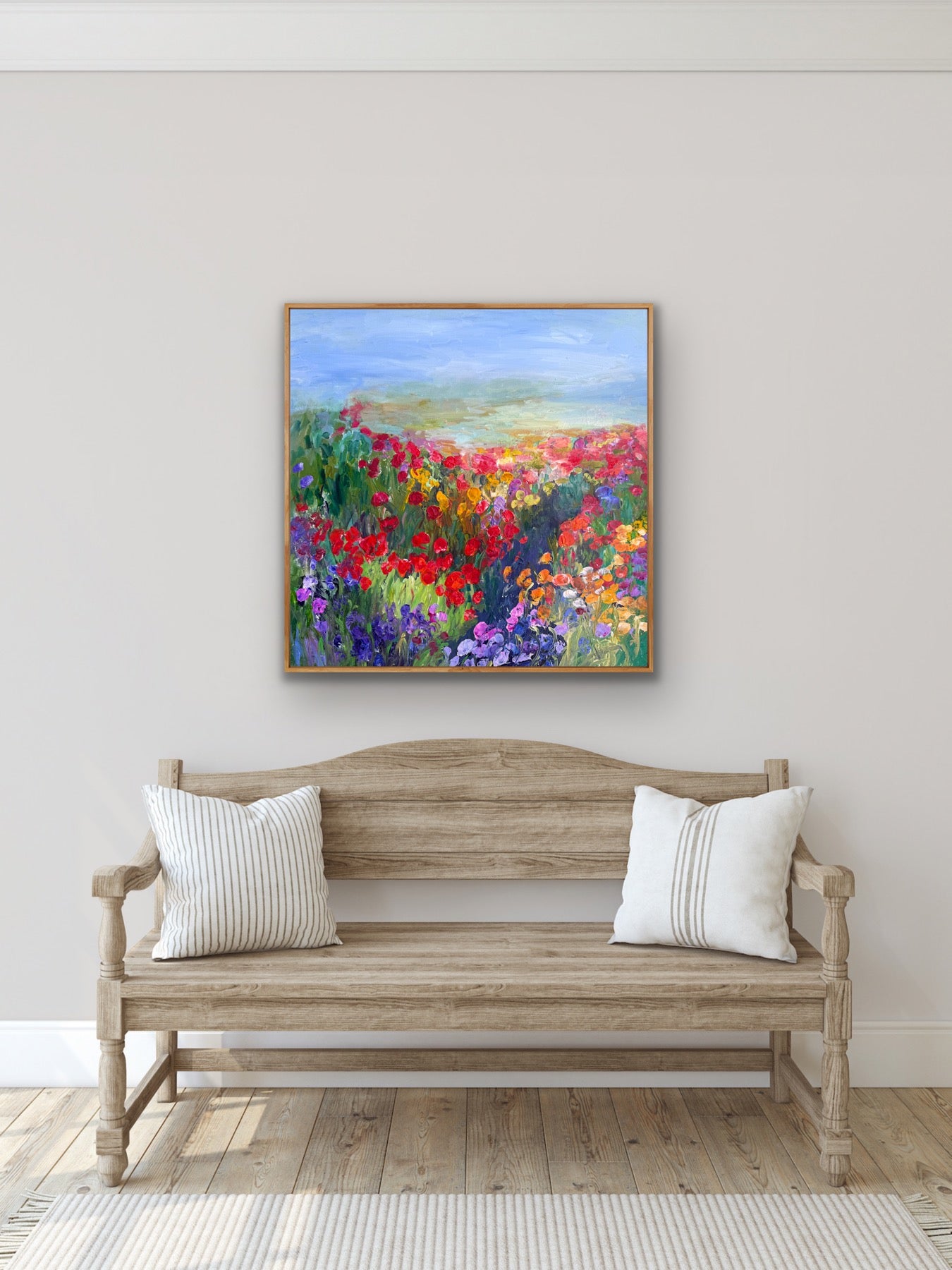 Framed impressionist landscape painting by Maria-Victoria Checa shown in a room above a bench.