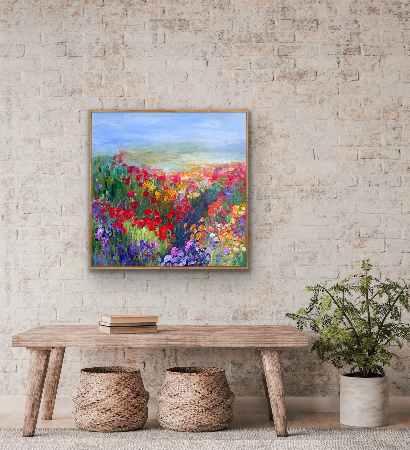 Framed impressionist landscape painting by Maria-Victoria Checa shown in a rustic room above a bench.