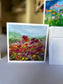 Poppy Field Greeting Card — 5×5 impressionist painting of red, magenta and yellow poppies under a soft blue-green sky with rolling hills, by Washington DC artist Maria-Victoria Checa