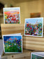 Three impressionist flower field greeting cards displayed on a wood box — prairie, wildflower meadow, and poppy field designs by Checa Art