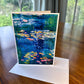 Water lily pond greeting card with deep blue water and luminous yellow and pink lily pads — impressionist art card by Maria-Victoria Checa
