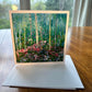 Birch forest greeting card with tall white tree trunks and pink wildflowers on a lush green forest floor — square impressionist art card by Maria-Victoria Checa