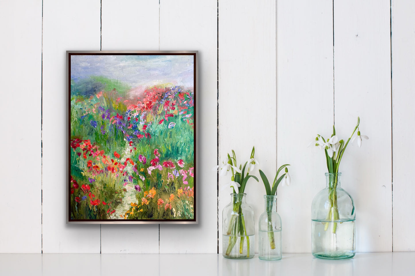 A Stroll in a Flower Field painting displayed in a bright modern interior with glass vases and white wood paneling.