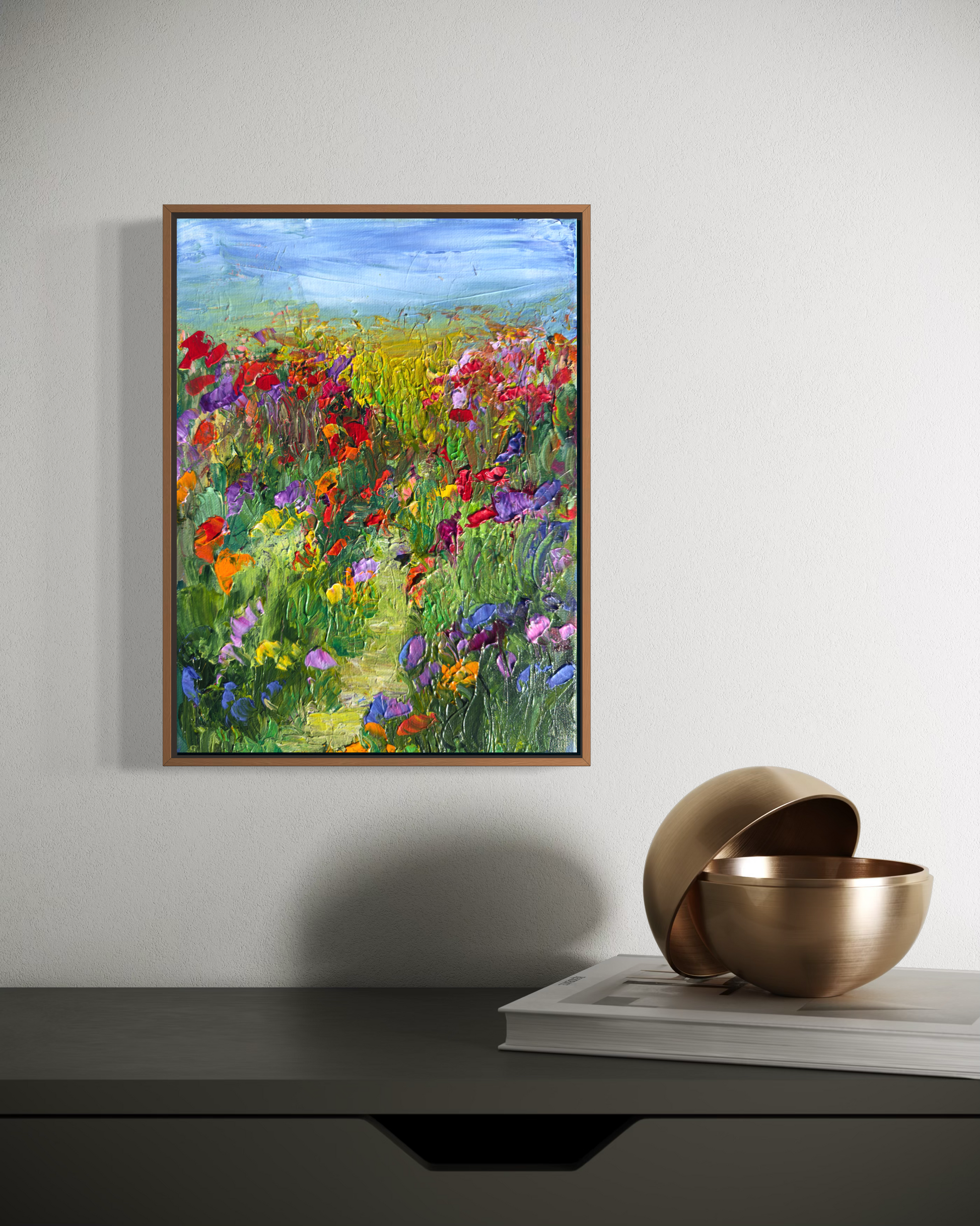 A Walk in a Flower Field painting displayed in a modern interior with a brass bowl and book on a console table