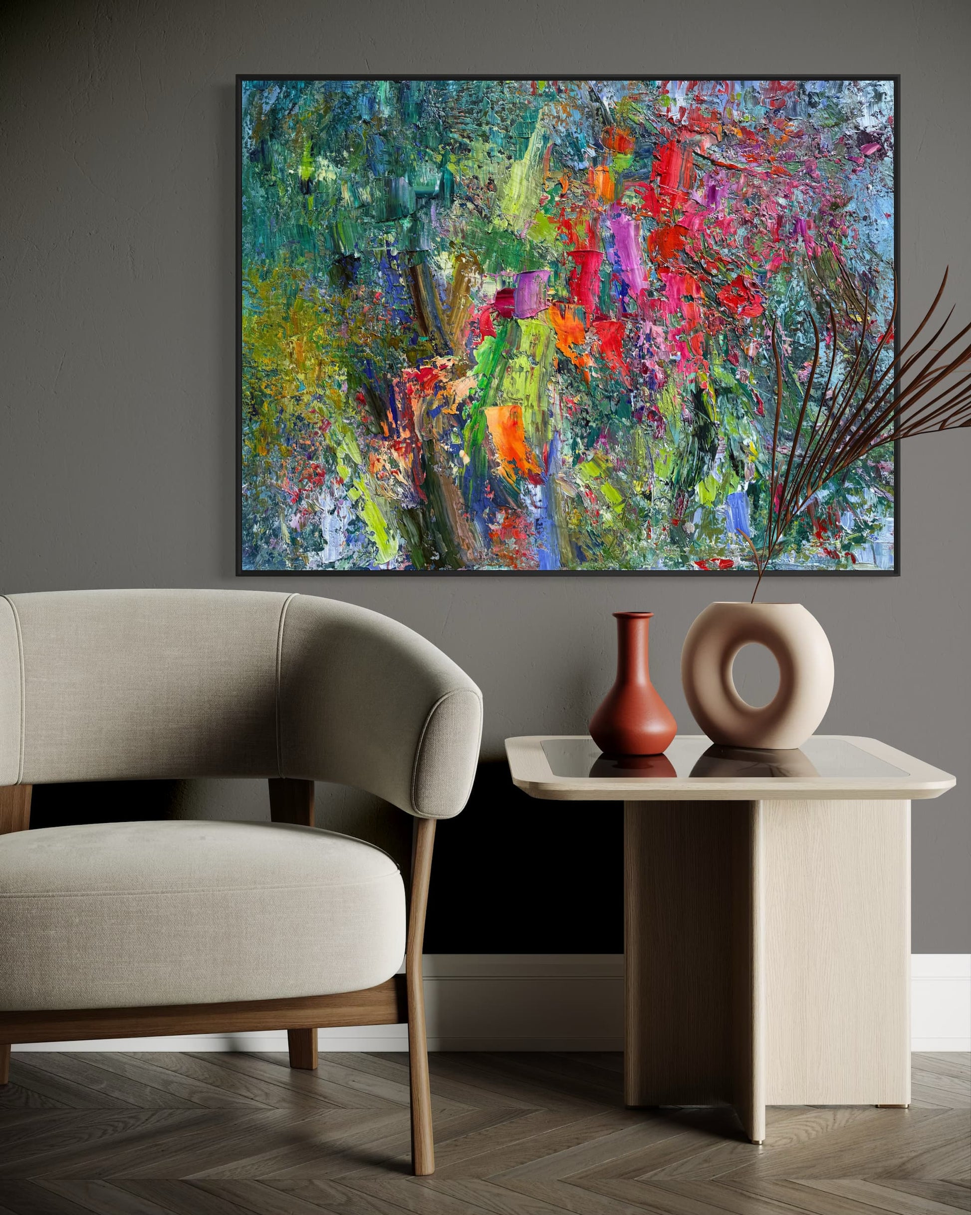 Abstract flower field oil painting in a warm modern living room above a side table with ceramic vases and a linen armchair