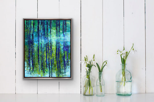"By the Bayou" original oil painting by Maria-Victoria Checa displayed in a dark float frame on a white shiplap wall beside glass vases with white snowdrop flowers — impressionist forest landscape in blue, green, and teal.