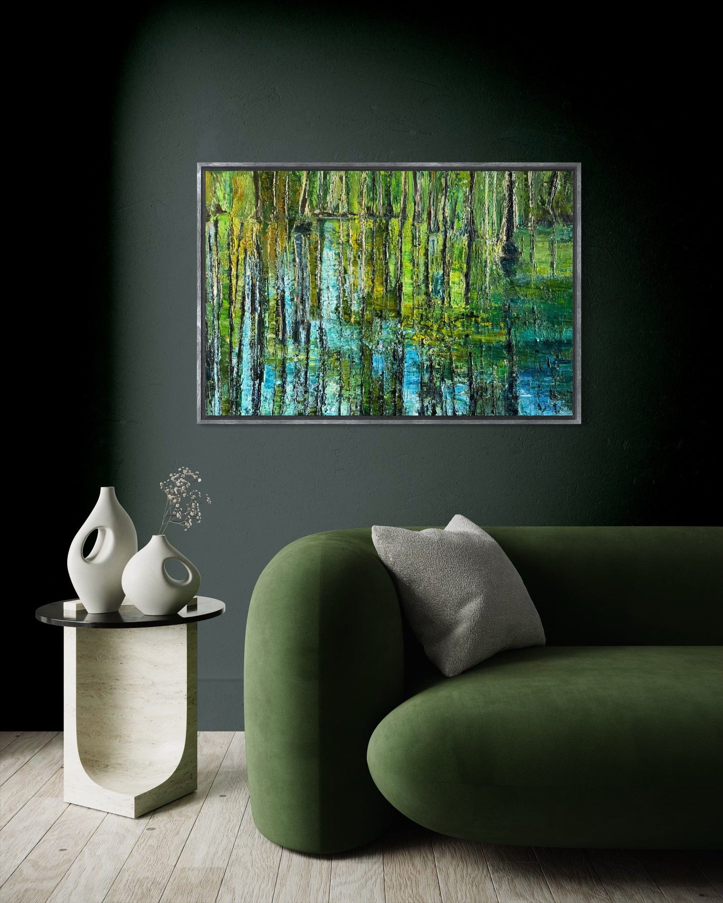 Framed impressionist landscape painting by Maria-Victoria Checa displayed on a dark wall behind a green sofa.