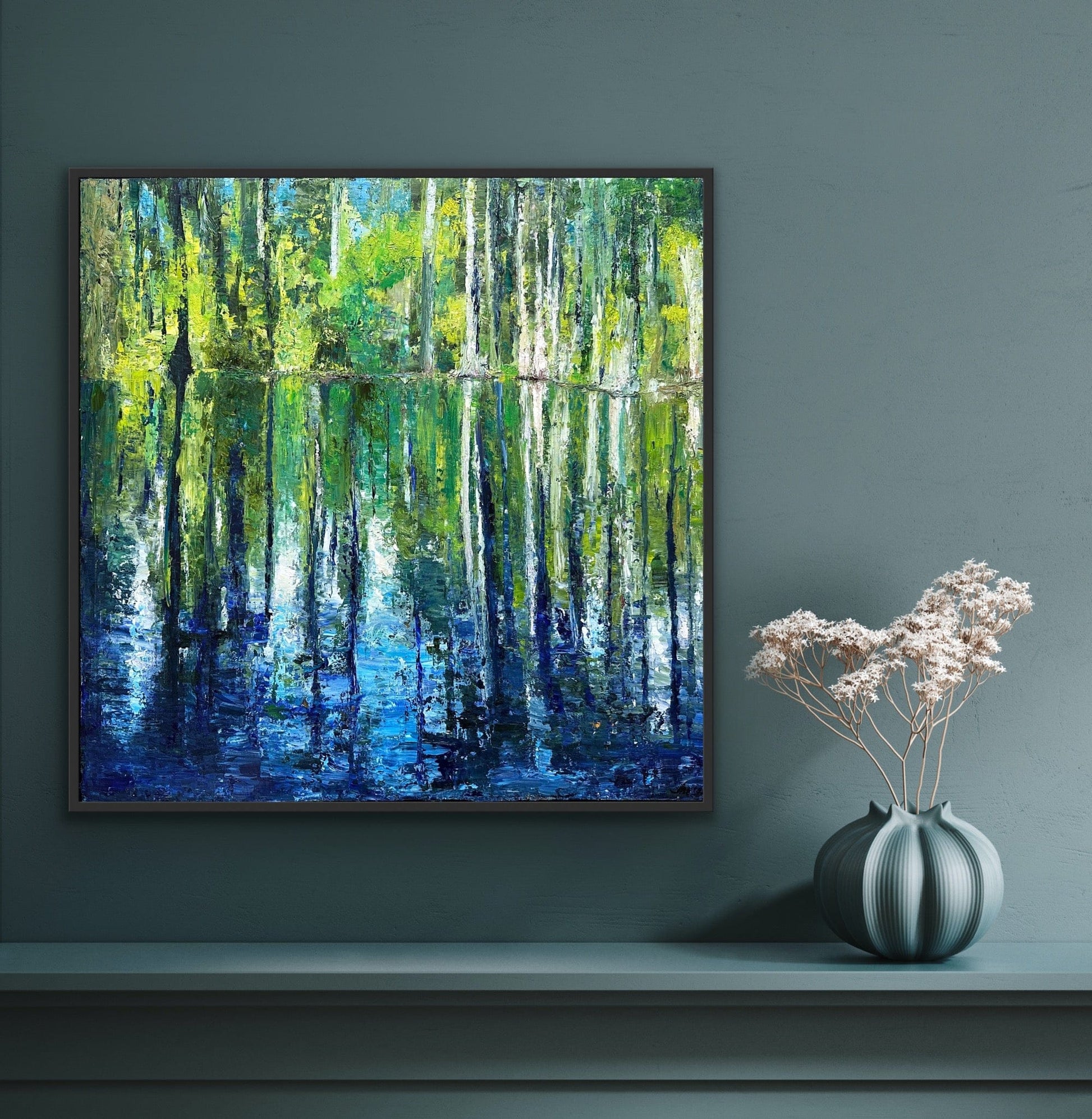 Cypress Gardens Reflection canvas print by Maria-Victoria Checa in a dark float frame displayed on a deep teal wall above a console table with a sculptural vase, showing scale in a moody modern interior