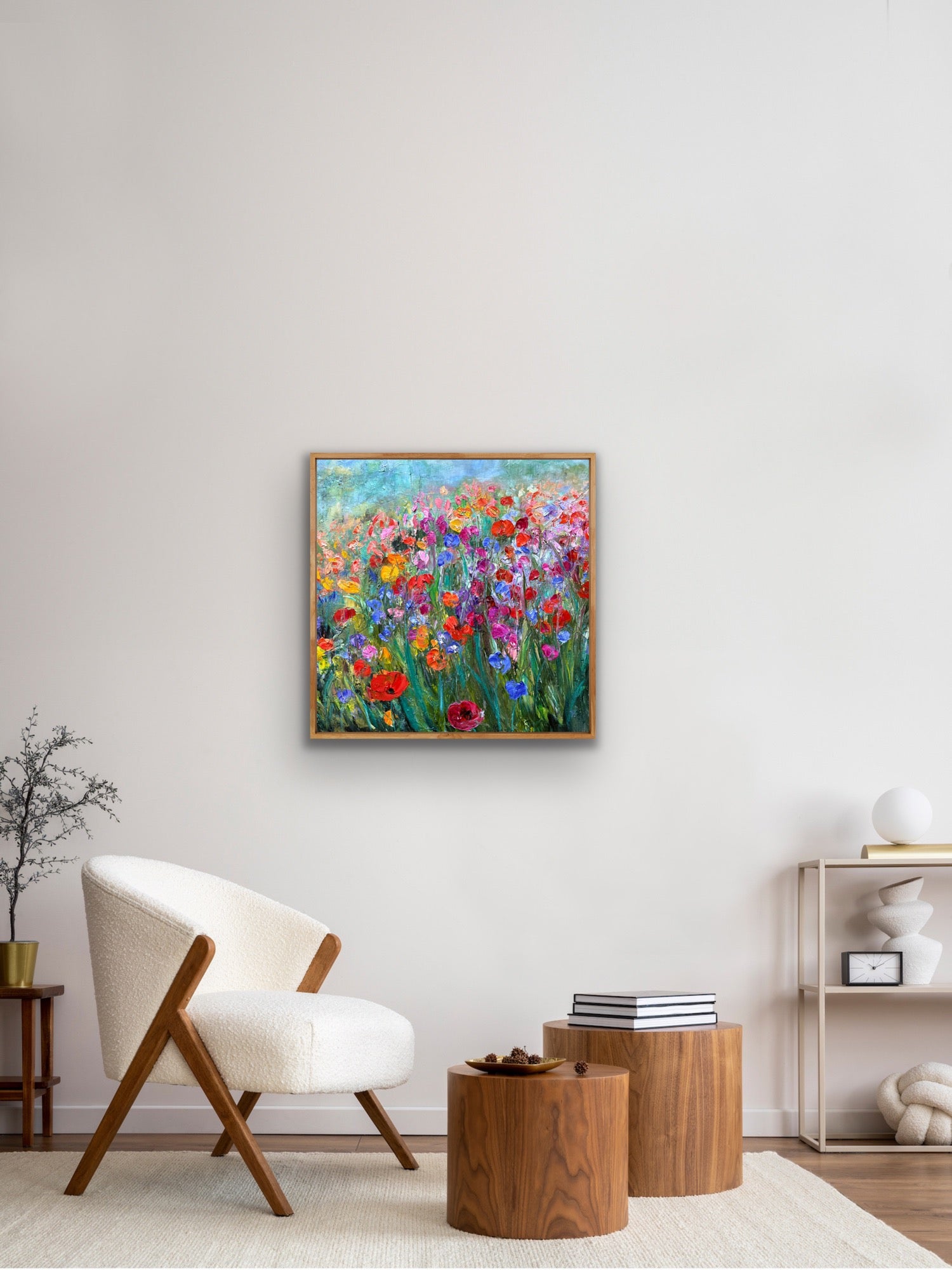 Colorful floral painting on a wall in a living room with a chair and tables.