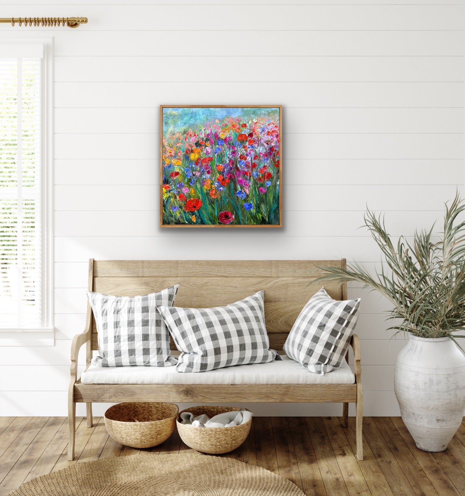 Living room with a wooden bench, checkered pillows, and a colorful floral painting on the wall.