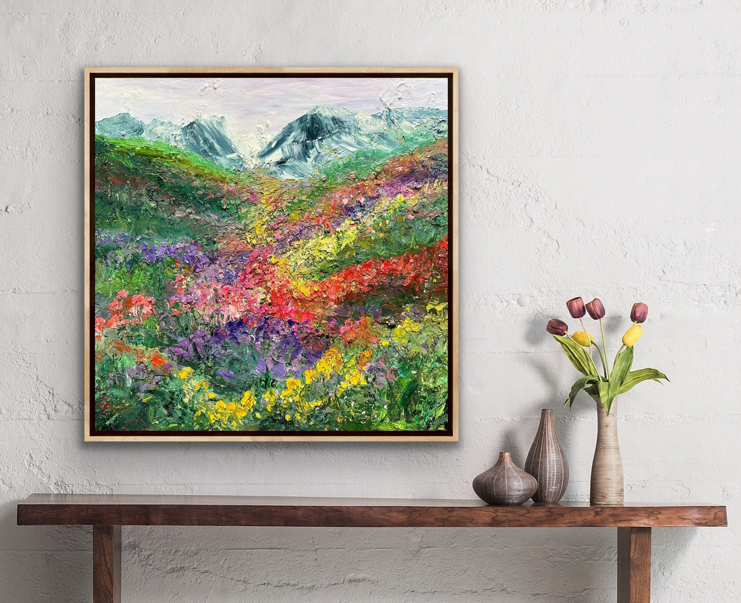 Happy Valley impressionist flower field painting by Maria-Victoria Checa in a natural wood float frame displayed on a white textured wall above a wooden console table in a warm bohemian room setting.