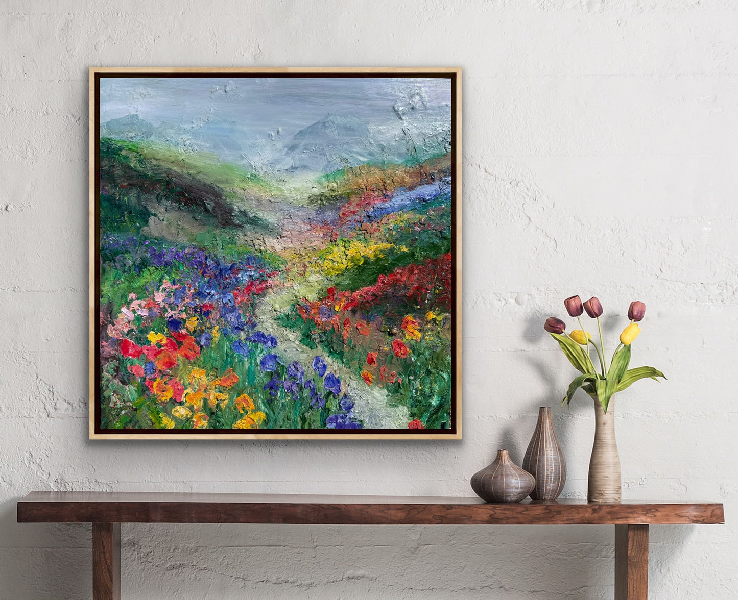 Happy Valley impressionist landscape painting by Maria-Victoria Checa in a natural wood float frame displayed on a white textured wall above a wooden console table in a warm bohemian interior