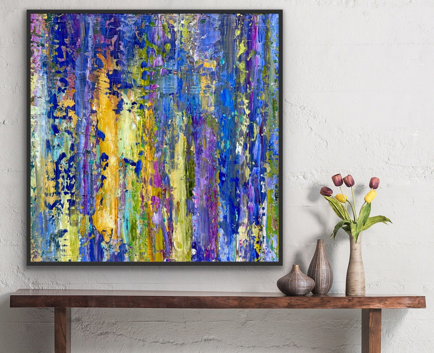 Lavender large abstract painting by Maria-Victoria Checa installed above a wooden console with decorative vases and tulips, showcasing layered blue, purple, and golden acrylic textures.