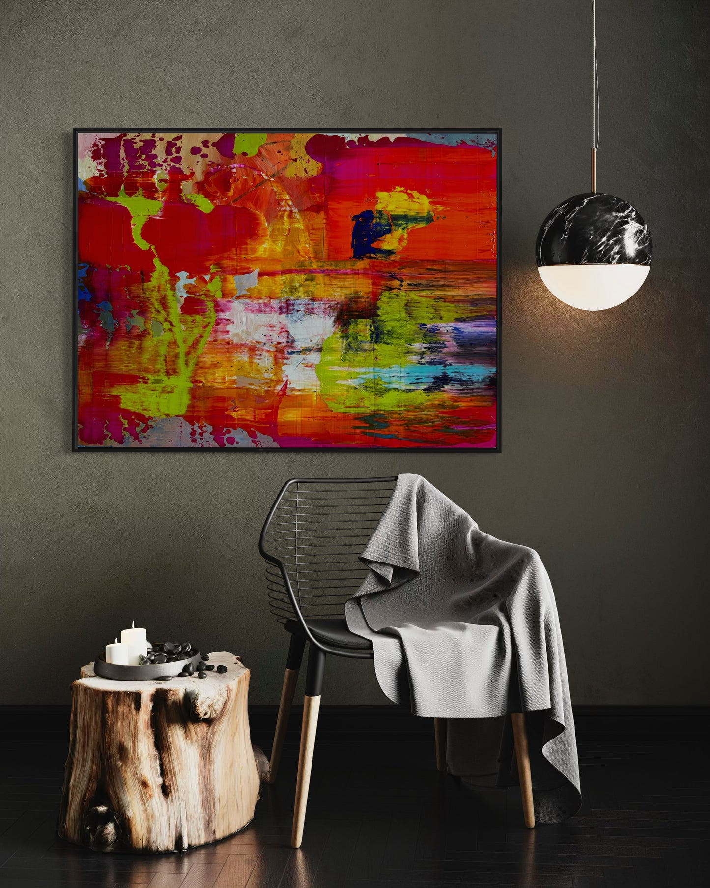 On Fire! abstract expressionist artwork hung above a dark modern chair with a blanket and sculptural pendant light, highlighting its vivid color contrasts.