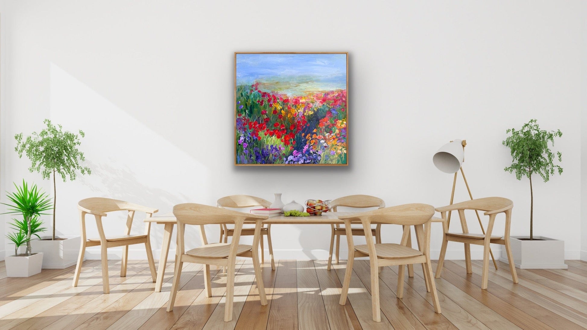 In-situ image of Path in the Meadow, a colorful impressionist flower landscape painting hanging in a modern dining room with natural wood furniture and indoor plants.