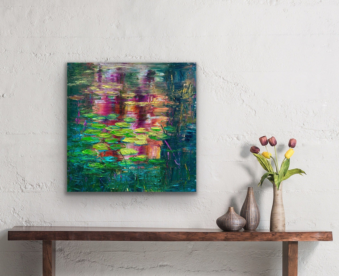 Sunset Lilies impressionist canvas print by Maria-Victoria Checa displayed on a white textured wall above a wooden console table, showing scale in a modern bohemian room setting