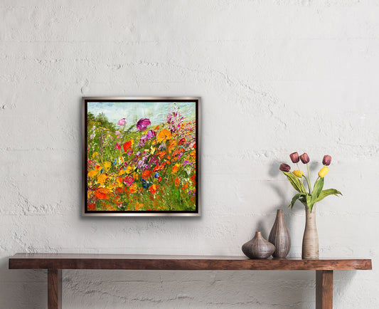 abstract impressionist oil painting of a flower field in tones of oranges and yellows on a wall next to tulips.